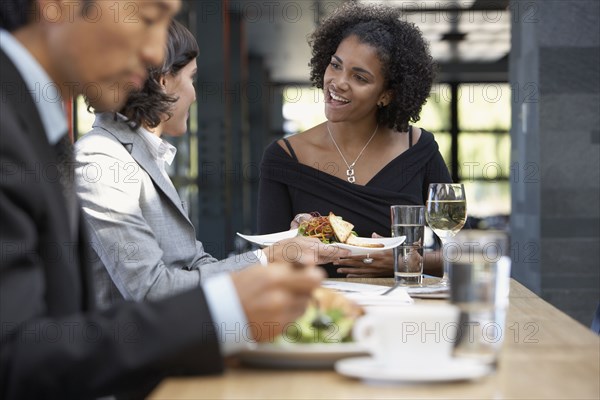 African waitress bringing food to businesswoman