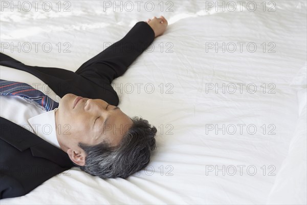 Asian businessman laying on bed