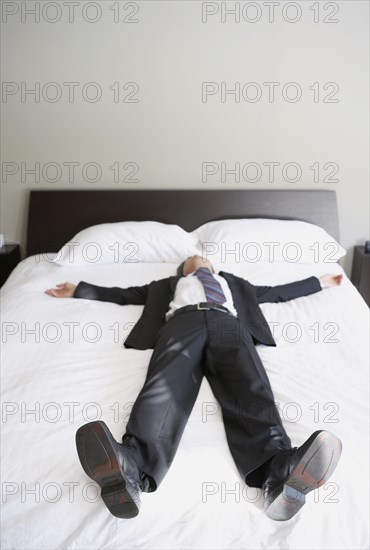 Asian businessman laying on bed