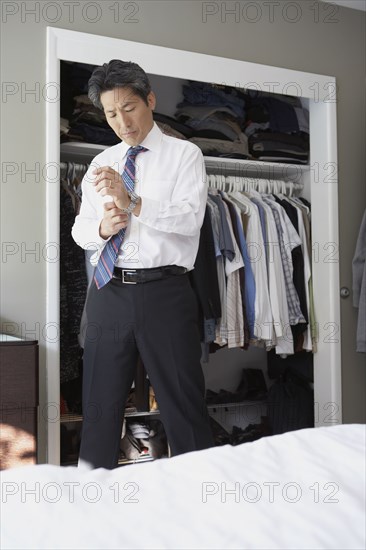 Asian businessman putting on watch