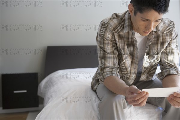 Asian man looking at photograph