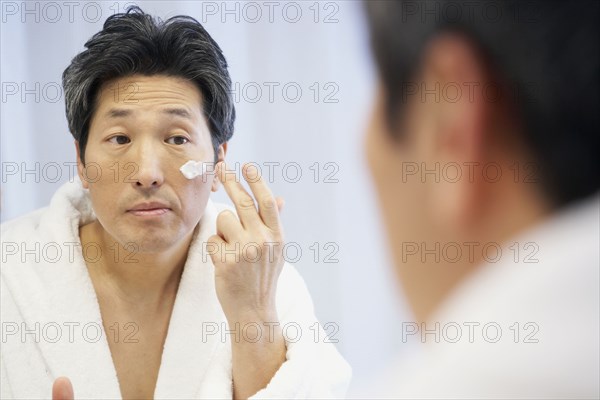 Asian man applying face cream