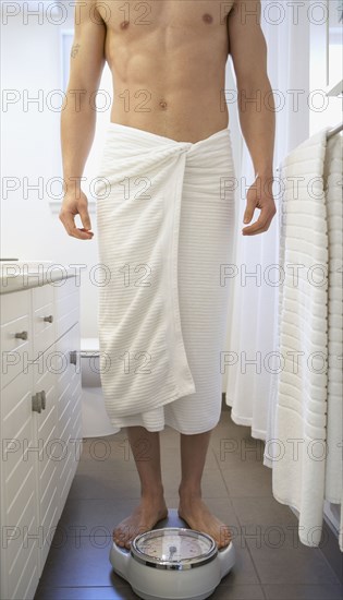 Asian man standing on bathroom scale