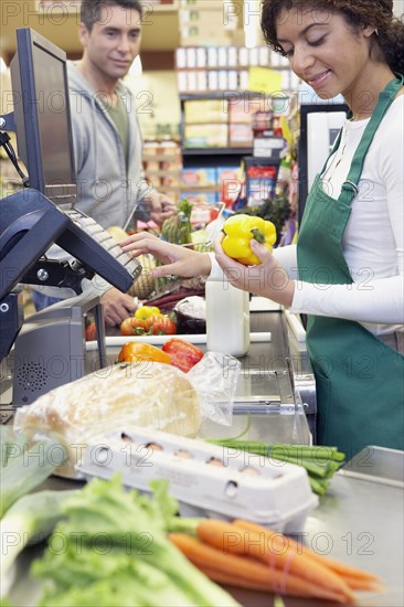 Mixed Race cashier ringing up groceries