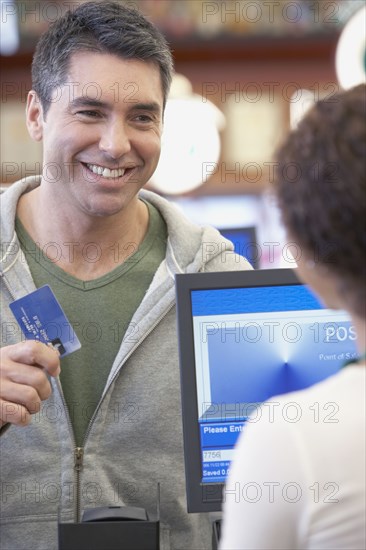 Hispanic man holding up credit card at check out