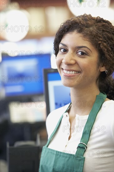 Mixed Race cashier wearing apron