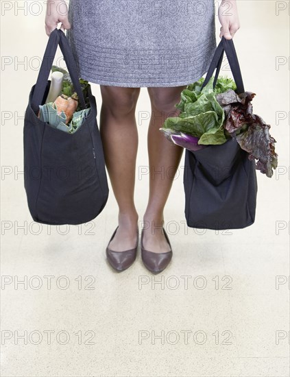 African woman holding reusable grocery bags