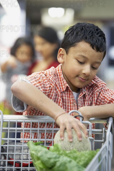 Indian boy putting fruit in shopping cart