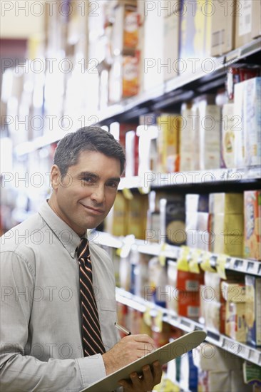 Hispanic grocery store manager holding clipboard