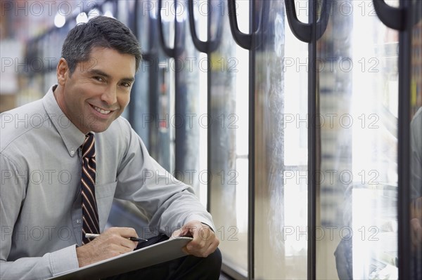 Hispanic grocery store manager holding clipboard