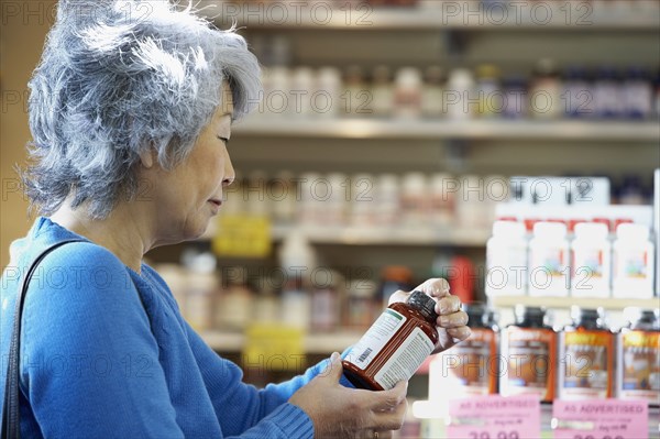 Senior Asian woman reading vitamin label