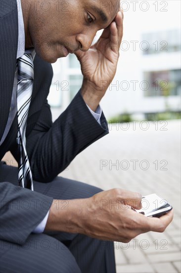 Mixed race businessman text messaging on cell phone