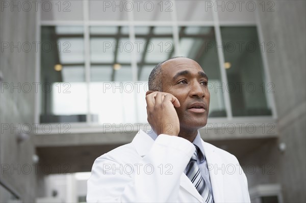 Mixed race doctor talking on cell phone outdoors