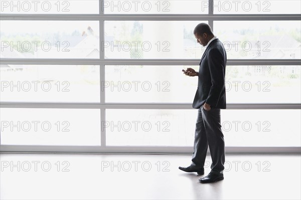 African businessman text messaging on cell phone