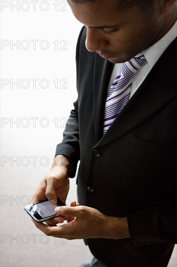 African businessman text messaging on cell phone