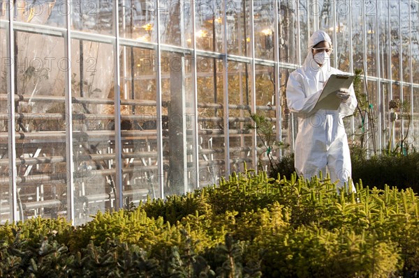 Scientist in clean suit working in greenhouse