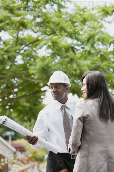 Woman talking to architect holding blueprints