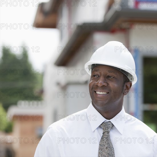 Smiling Black real estate agent in hard-hat near construction site