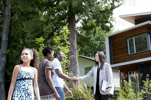 Real estate agent greeting family at house