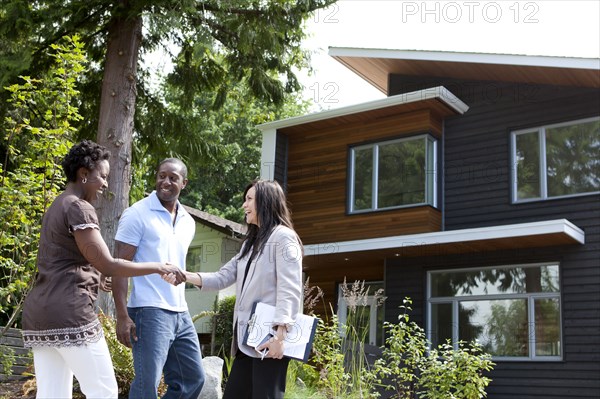 Real estate agent greeting couple at house