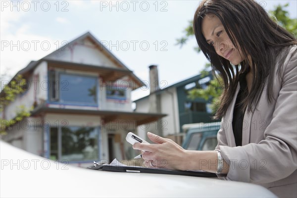 Mixed race real estate agent standing near house under construction