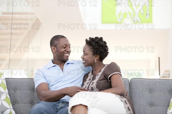 Happy Black couple sitting on sofa in living room