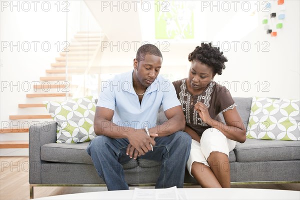 Serious Black couple sitting on sofa together