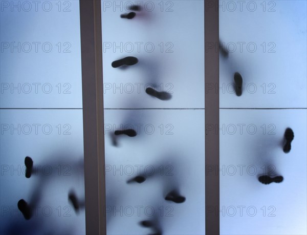 Silhouette of feet standing on glass ceiling