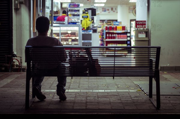 Man sitting on city bench at night