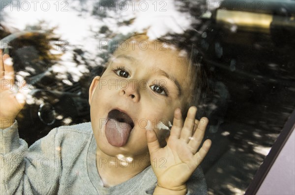 Hispanic boy licking car window