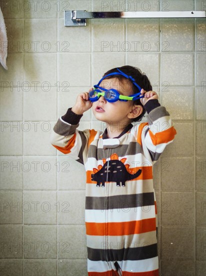 Hispanic boy playing with goggles in bathroom