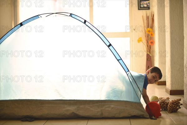 Hispanic boy camping in tent indoors