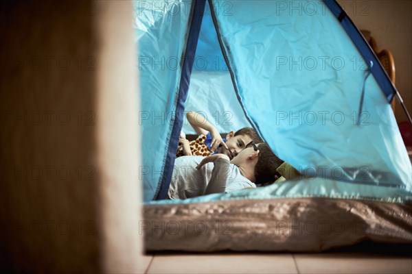 Hispanic boys camping in tent indoors