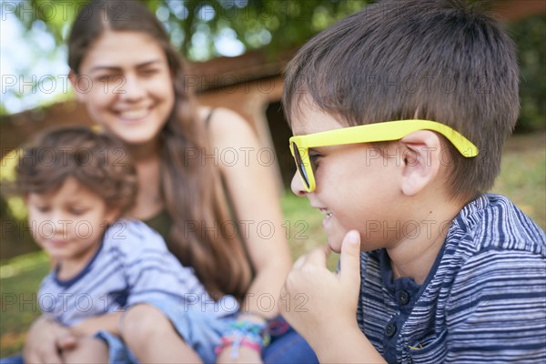Hispanic mother and sons sitting in grass outdoors