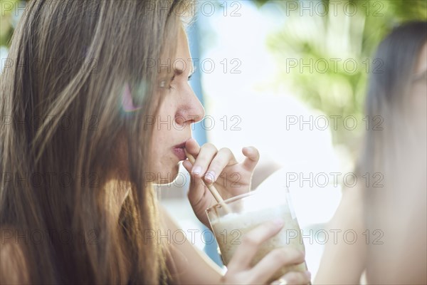 Hispanic woman drinking milkshake with straw