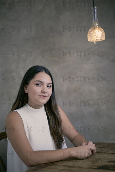 Smiling Hispanic woman sitting at wooden table