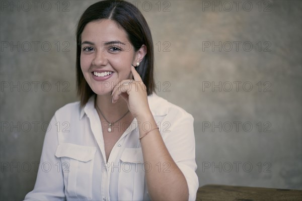 Smiling Hispanic woman sitting at wooden table