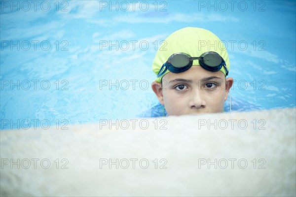 Hispanic boy swimming with swimming cap and goggles