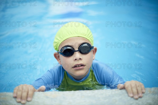 Hispanic boy swimming with swimming cap and goggles