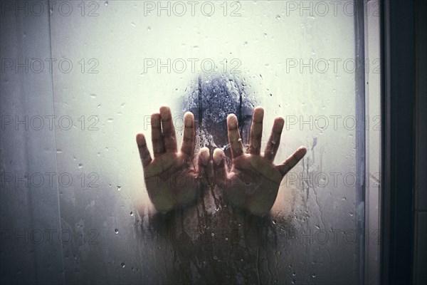 Hands of Hispanic boy leaning on shower door