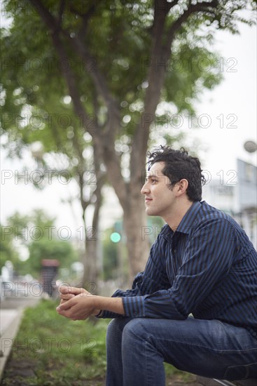 Smiling Hispanic man sitting on bench