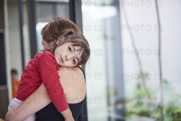 Hispanic mother carrying tired daughter