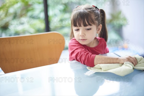 Hispanic girl cleaning table with towel