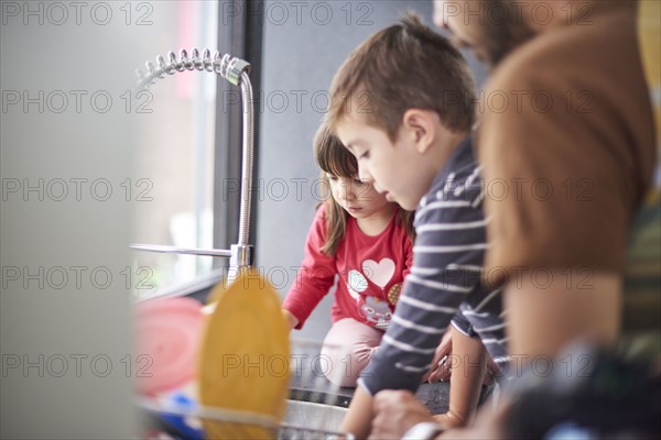 Hispanic family washing dishes at sink