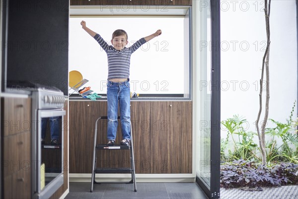 Hispanic boy cheering on ladder