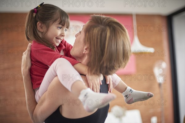 Playful Hispanic mother carrying daughter