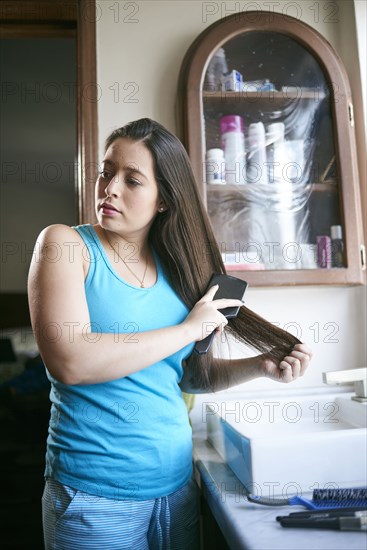 Hispanic woman wearing pajamas brushing hair