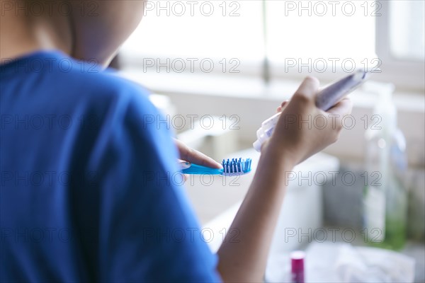 Hispanic by squeezing toothpaste onto toothbrush