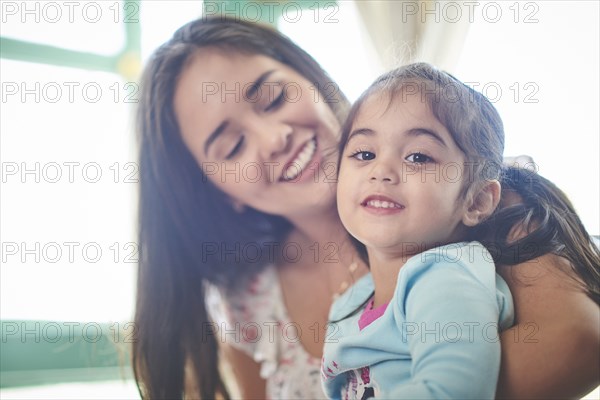 Hispanic mother holding smiling daughter