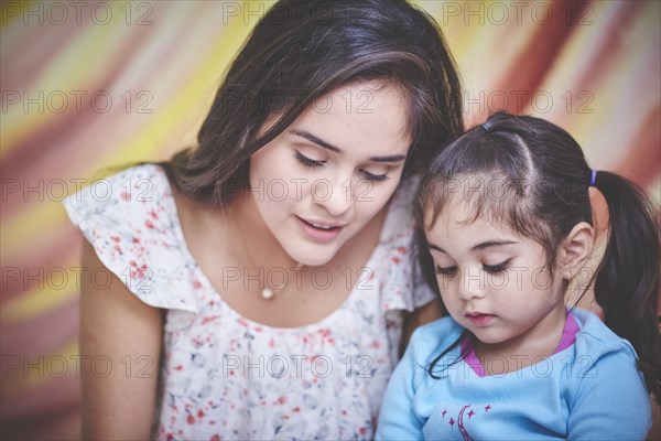 Hispanic mother and daughter looking down